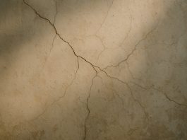 Les signes invisibles qui peuvent fragiliser un bâtiment Gros plan de fissures sur un vieux mur en plâtre