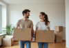 Jeune couple souriant avec cartons dans appartement moderne
